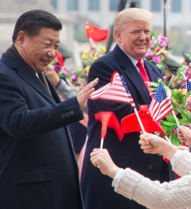 Trump and Xi walking past crowds of children waving small US and Chinese flags.